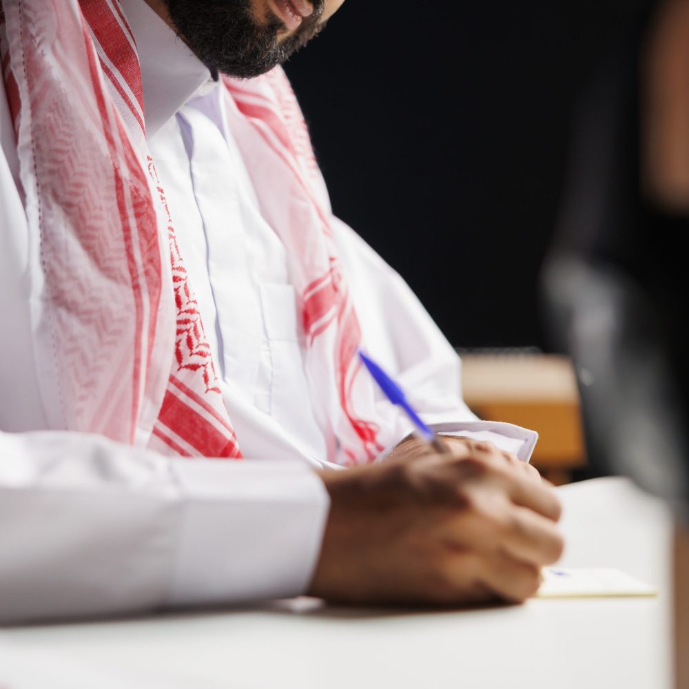 Islamic man works at table with notepad